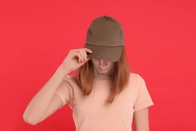 Photo of Woman in stylish baseball cap on red background. Mockup for design