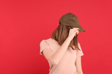 Photo of Woman in stylish baseball cap on red background. Mockup for design