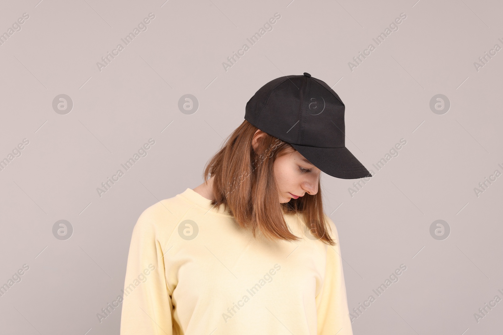 Photo of Woman in stylish baseball cap on grey background. Mockup for design