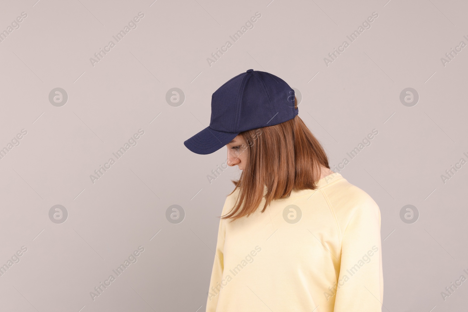 Photo of Woman in stylish baseball cap on grey background. Mockup for design