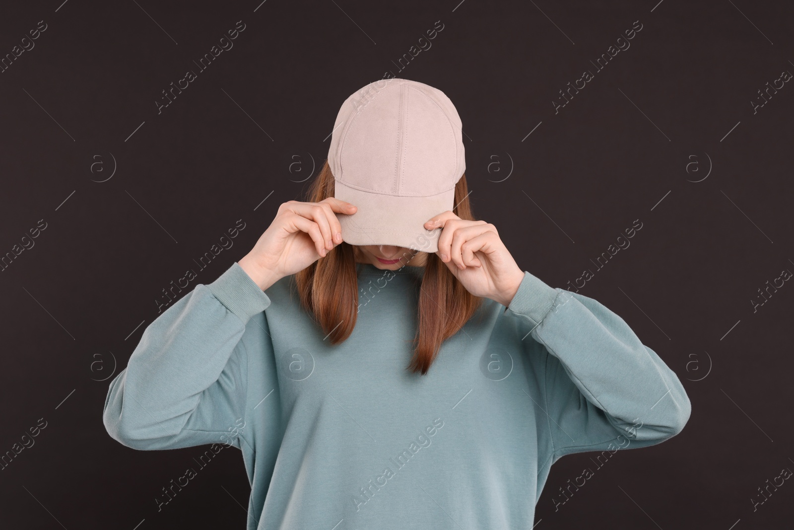 Photo of Woman in stylish baseball cap on black background. Mockup for design