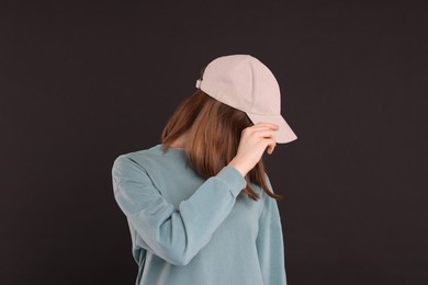 Photo of Woman in stylish baseball cap on black background. Mockup for design