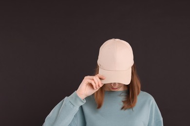 Photo of Woman in stylish baseball cap on black background. Mockup for design