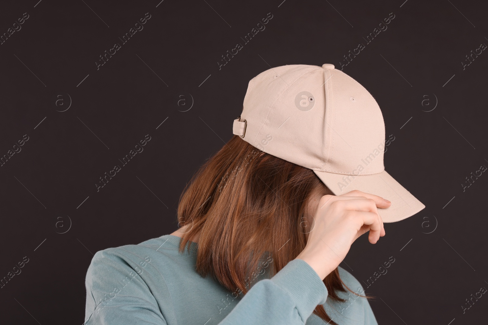 Photo of Woman in stylish baseball cap on black background. Mockup for design