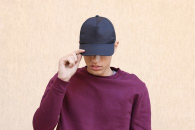 Photo of Man in stylish baseball cap near beige wall. Mockup for design