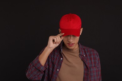 Photo of Man in stylish baseball cap on black background. Mockup for design