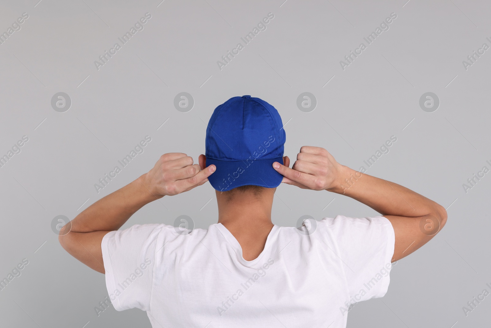 Photo of Man in stylish baseball cap on grey background, back view. Mockup for design