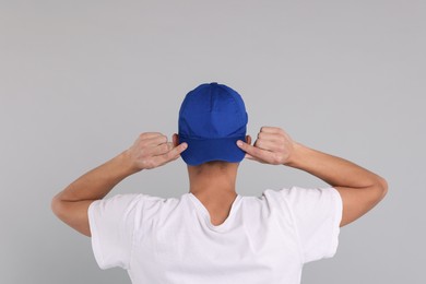 Photo of Man in stylish baseball cap on grey background, back view. Mockup for design