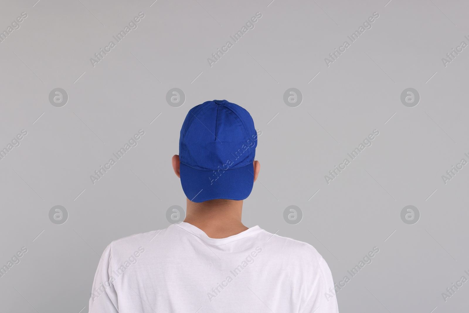 Photo of Man in stylish baseball cap on grey background, back view. Mockup for design