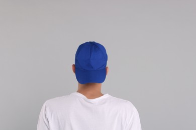 Photo of Man in stylish baseball cap on grey background, back view. Mockup for design