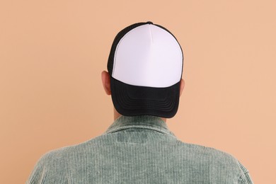 Photo of Man in stylish baseball cap on beige background, back view. Mockup for design