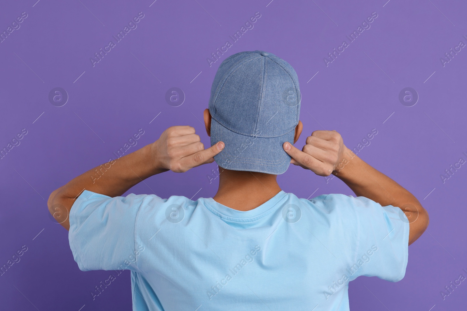 Photo of Man in stylish baseball cap on violet background, back view. Mockup for design