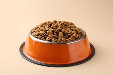 Photo of Dry pet food in feeding bowl on beige background