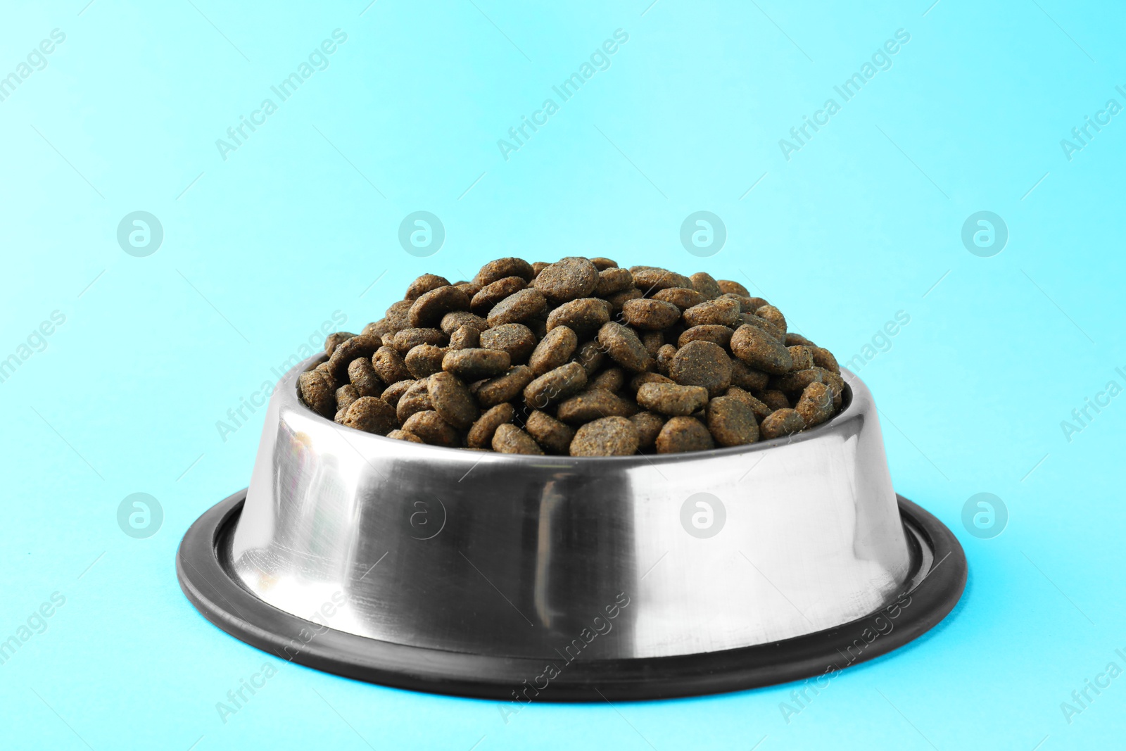 Photo of Dry pet food in feeding bowl on light blue background