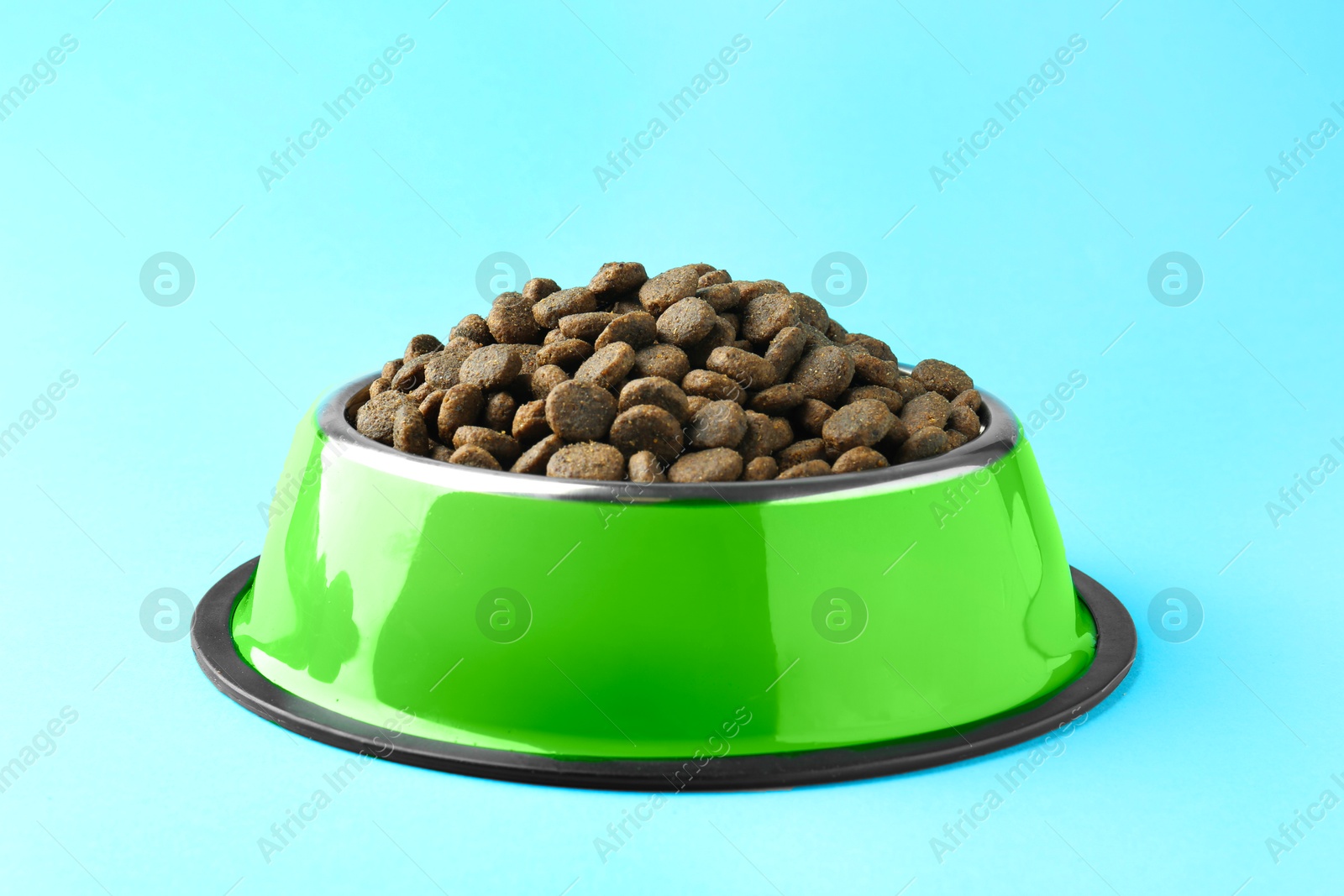 Photo of Dry pet food in feeding bowl on light blue background