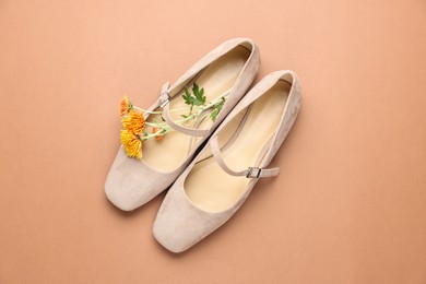 Photo of Pair of ballet flats and flowers on beige background, top view