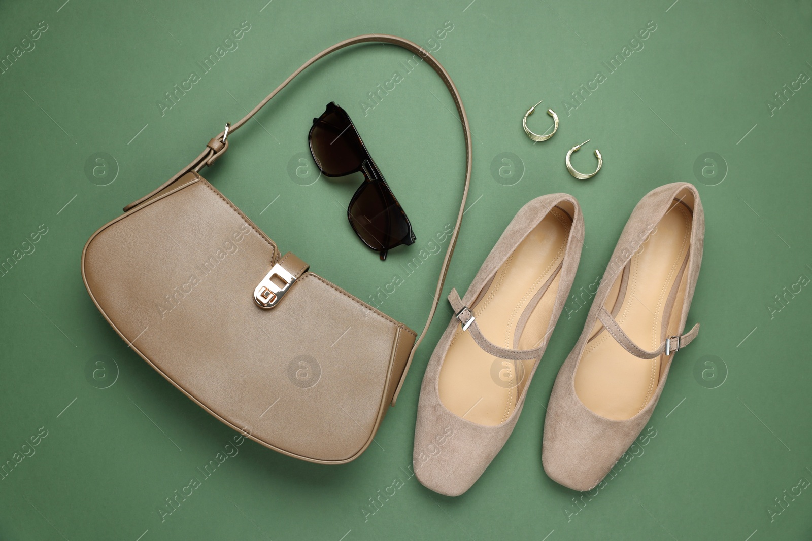 Photo of Pair of ballet flats, bag, sunglasses and earrings on green background, flat lay