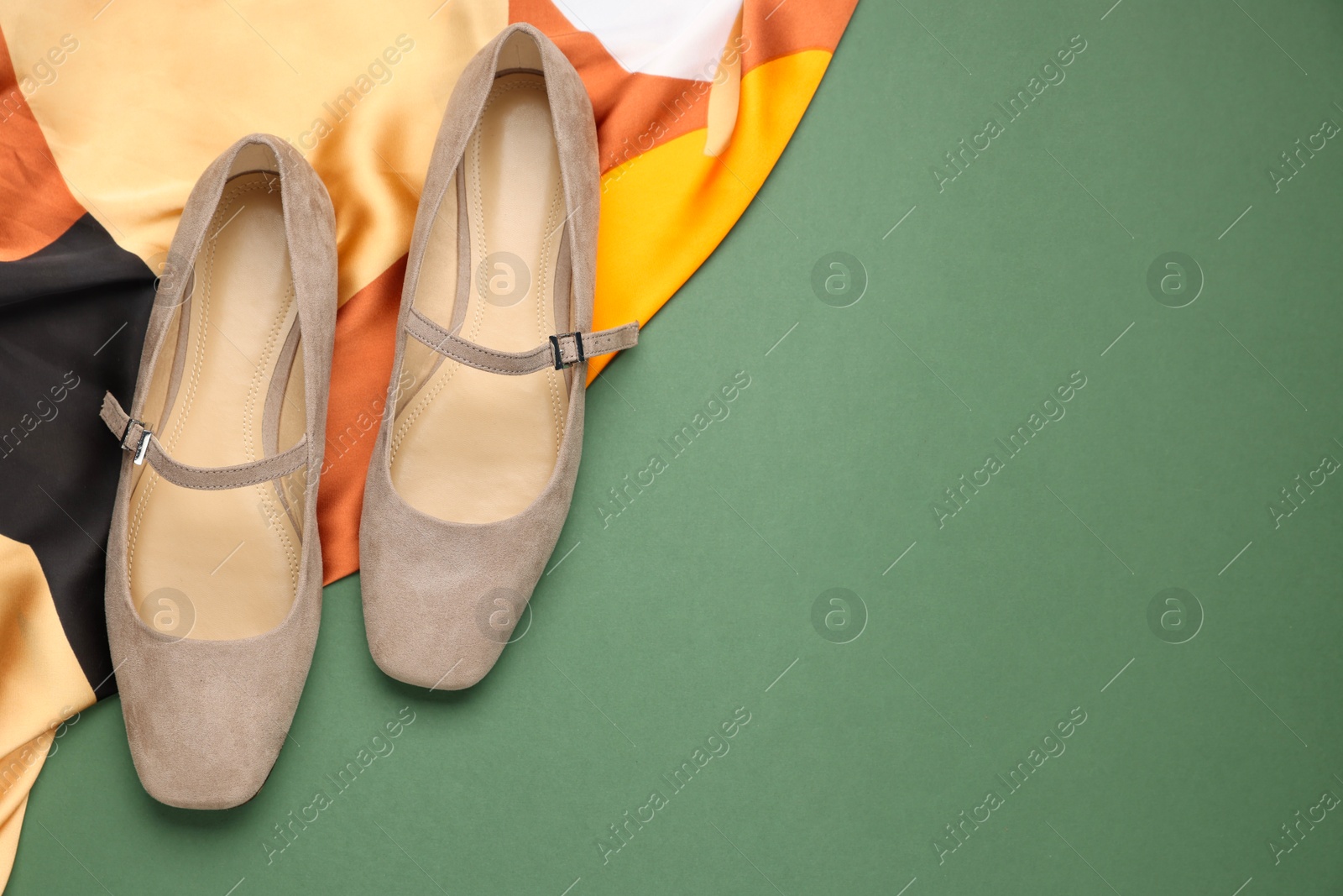 Photo of Pair of ballet flats and scarf on green background, top view. Space for text