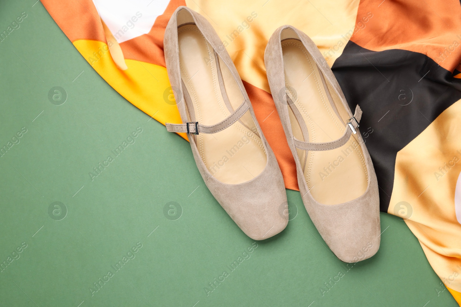 Photo of Pair of ballet flats and scarf on green background, top view. Space for text