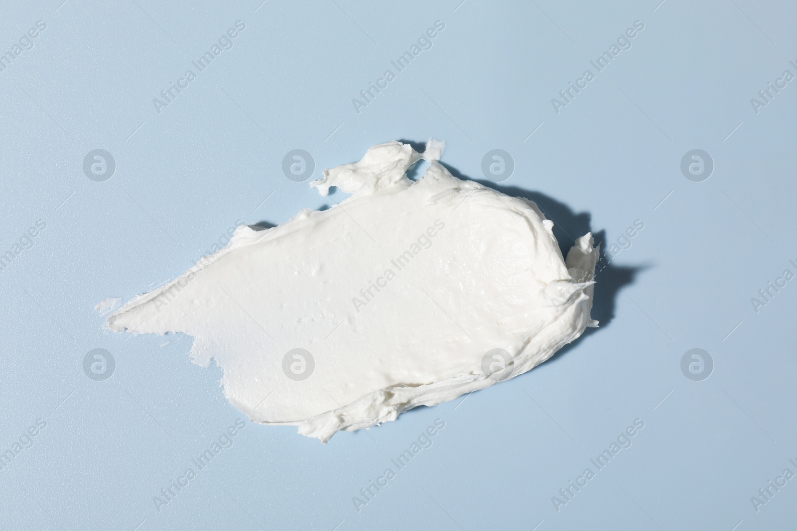 Photo of Sample of cream on light blue background, top view