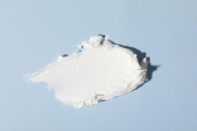 Photo of Sample of cream on light blue background, top view