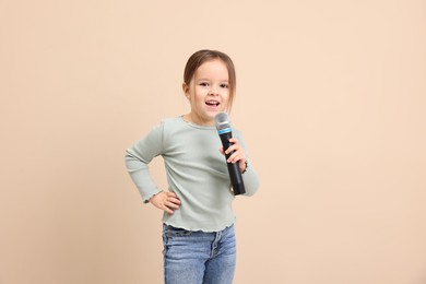 Photo of Cute girl with microphone singing near beige wall