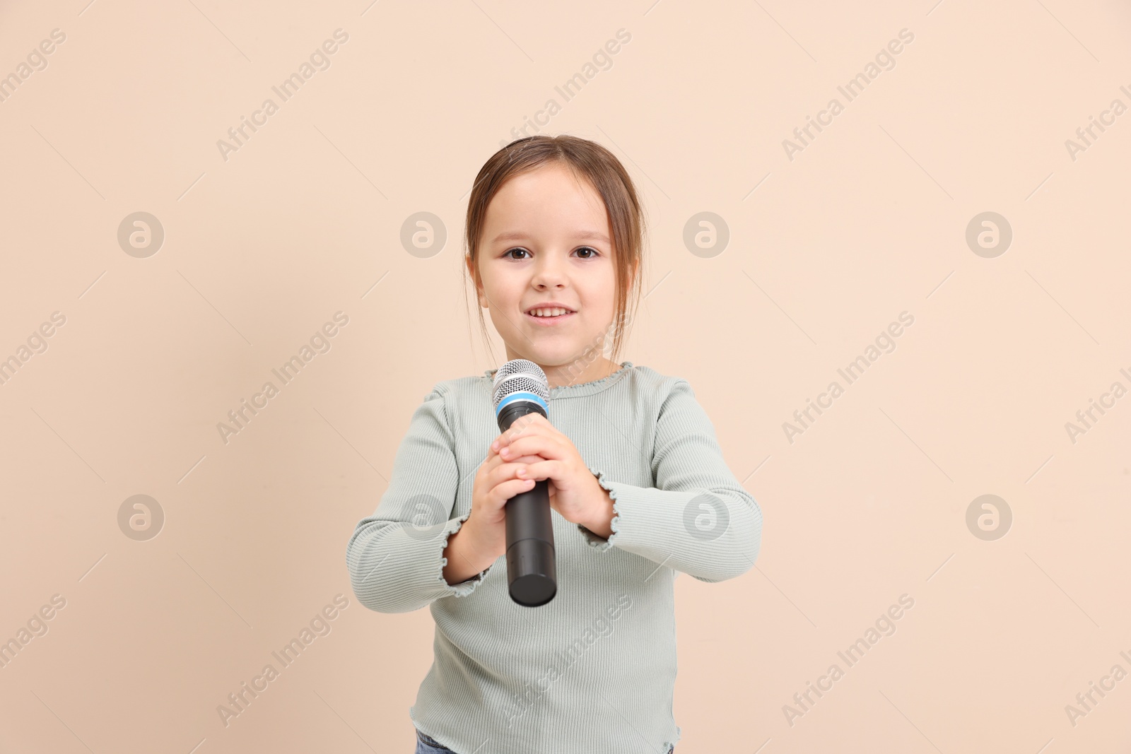 Photo of Smiling girl with microphone near beige wall