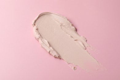 Photo of Cream on pink background, above view. Sample of cosmetic product