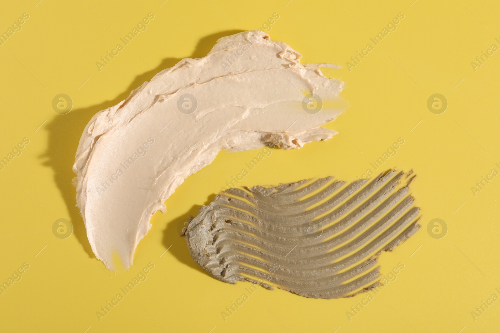 Photo of Samples of cosmetic products on yellow background, top view