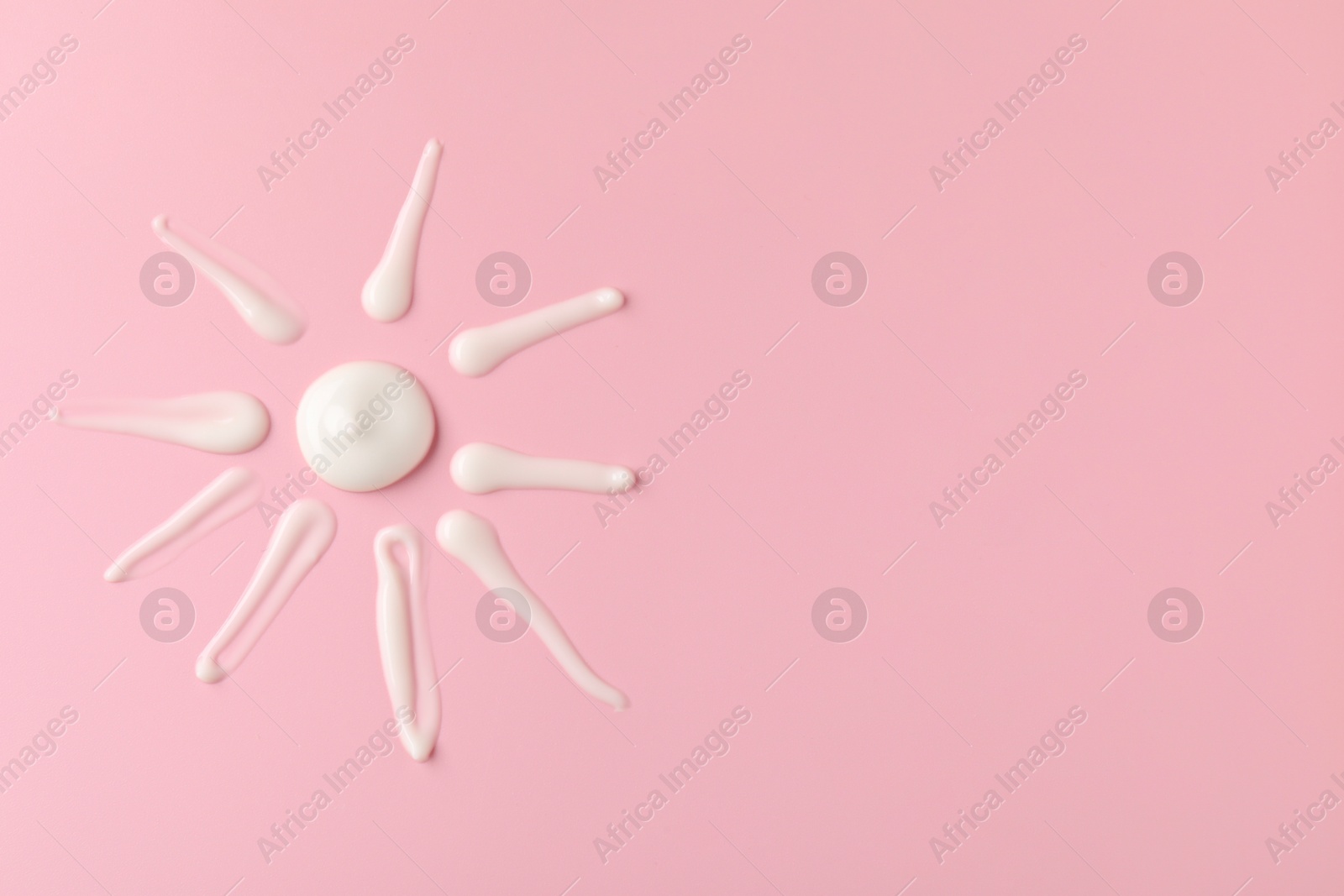 Photo of Sun shape made of cream on pink background, top view and space for text. Samples of cosmetic product