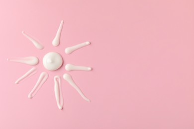 Photo of Sun shape made of cream on pink background, top view and space for text. Samples of cosmetic product