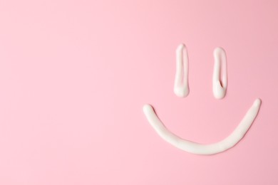 Photo of Smiling face made of cream on pink background, top view. Samples of cosmetic product. Space for text