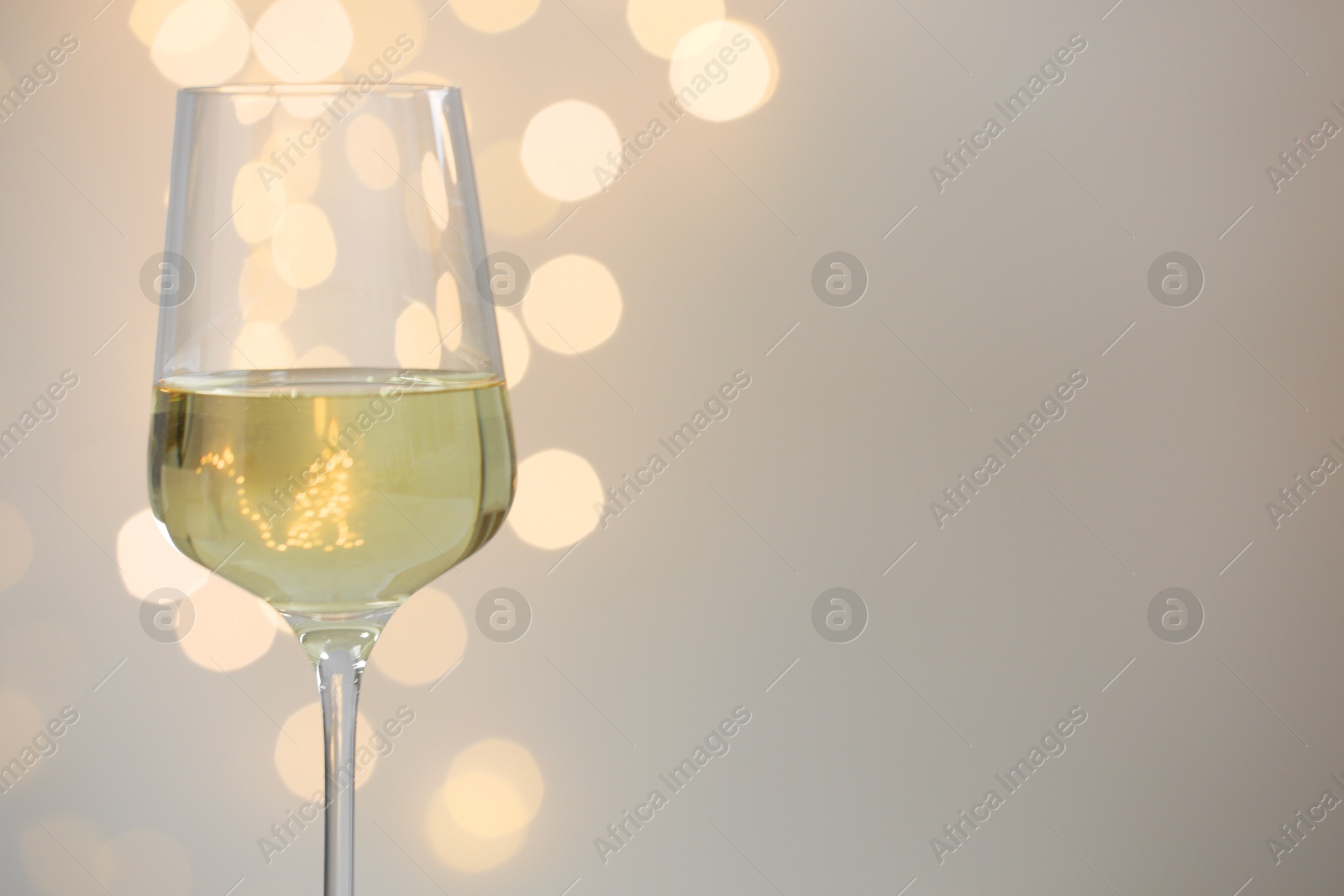 Tasty white wine in glass against grey background with blurred lights, closeup. Bokeh effect Photo of Tasty white wine in glass against grey background with blurred lights, closeup. Bokeh effect