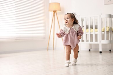 Photo of First steps. Cute little baby learning to walk at home, space for text