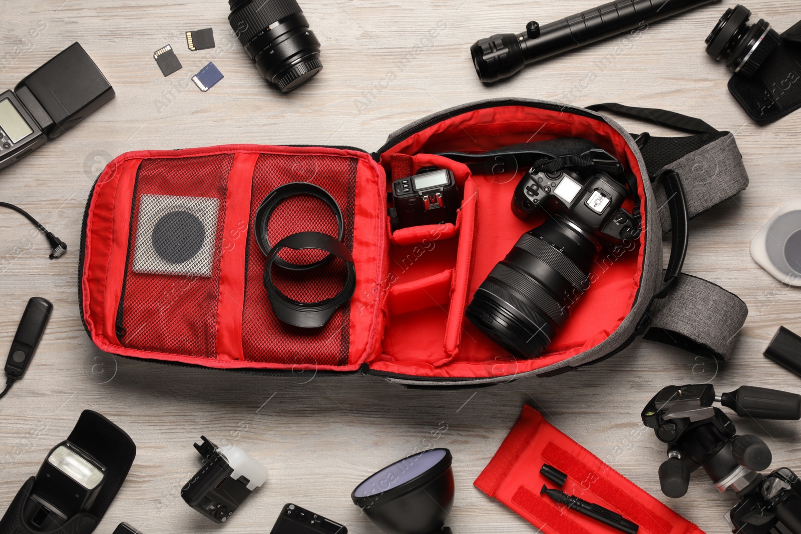 Photo of Professional photographer's equipment and backpack on light wooden background, flat lay