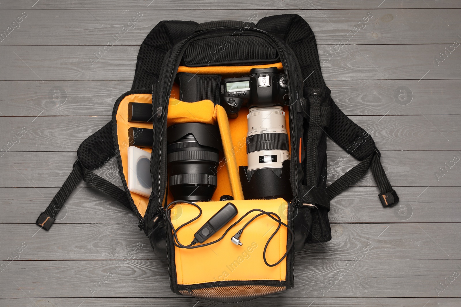 Photo of Professional photographer's equipment and backpack on grey wooden background, flat lay