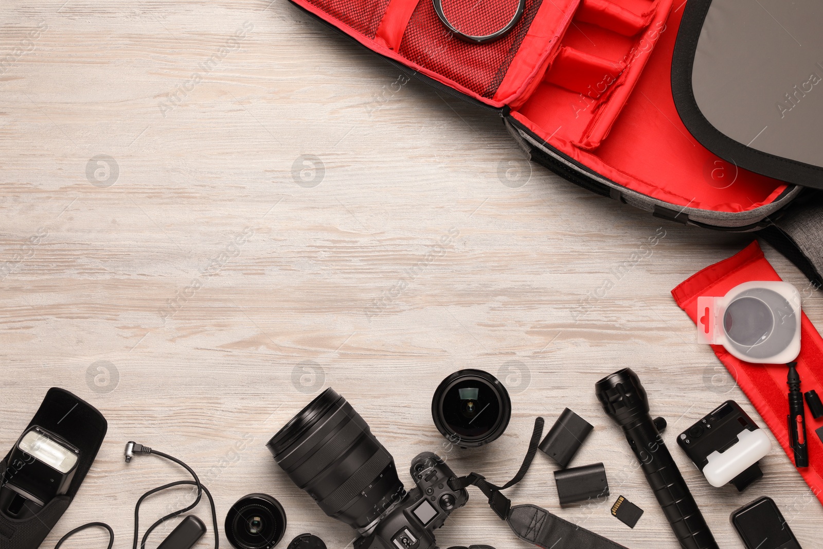 Photo of Professional photographer's equipment and backpack on light wooden background, flat lay. Space for text