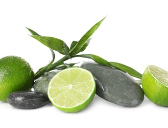 Photo of Spa composition with limes, massage stones and green leaves isolated on white