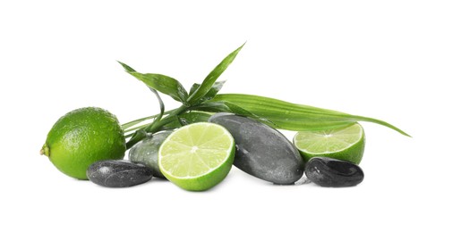 Photo of Spa composition with limes, massage stones and green leaves isolated on white