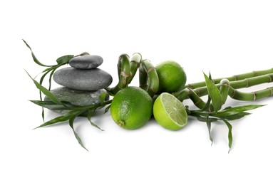 Photo of Spa composition with limes, massage stones and bamboo stems isolated on white