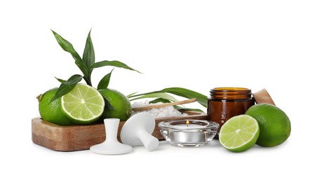 Photo of Spa composition with limes, massage stones, burning candle, sea salt and green leaves isolated on white