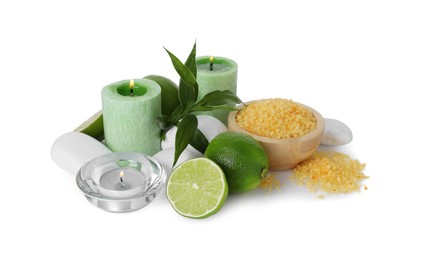 Photo of Spa composition with limes, massage stones, burning candles, sea salt and green leaves isolated on white