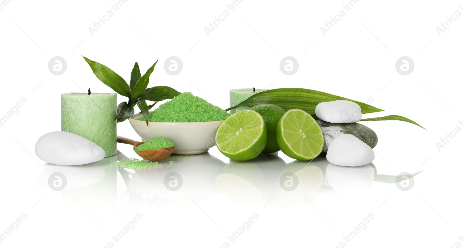 Photo of Spa composition with fresh limes, sea salt, massage stones and bamboo leaves on mirror surface against white background
