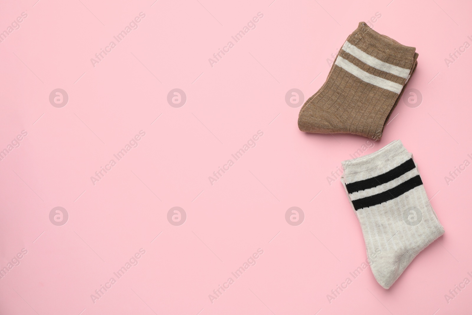 Photo of Different comfortable socks on light pink background, flat lay. Space for text