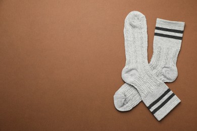 Photo of Pair of soft comfortable socks on brown background, top view. Space for text