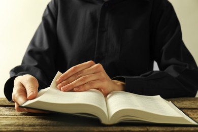 Woman reading Holy Bible in English language at wooden table, closeup