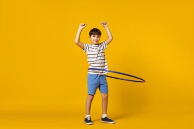 Photo of Boy exercising with hula hoop on yellow background