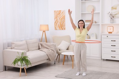 Photo of Smiling woman training with hula hoop at home