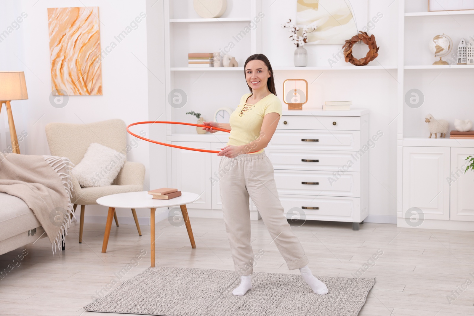 Photo of Smiling woman training with hula hoop at home