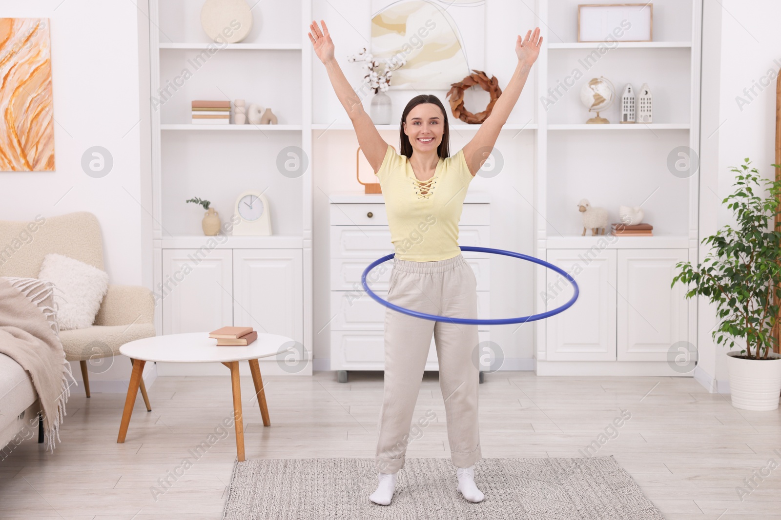 Photo of Smiling woman training with hula hoop at home